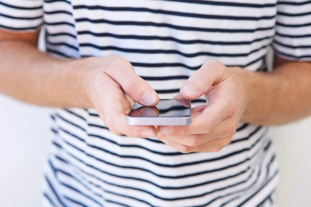 close-up-young-man-holding-mobile-phone-in-hands-NSWZHXD0